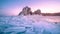 Landscape of Shamanka rock at sunrise with natural breaking ice in frozen water on Lake Baikal