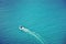 A landscape of a ship sailing off the shore, showing a beautiful long stern wave on blue sea background with selective focus on