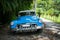 Landscape shot of a blue antique car in a tropical area