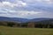 Landscape shot of clouds, grass and mountains in Germany, Vulkaneifel in Rhineland-Palatinate in spring