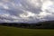 Landscape shot of clouds, grass and mountains in Germany, Vulkaneifel in Rhineland-Palatinate in spring