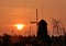 Landscape shot of a silhouette of a windmill in the field during a breathtaking golden sunset