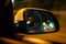 Landscape in the sideview mirror of a car , on the night road. In the side mirror of the car is reflected the lights of the night