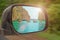 Landscape in the sideview mirror of a car , on road countryside. In the side mirror of the car is reflected the sea of rocks and