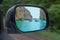 Landscape in the sideview mirror of a car , on road countryside. In the side mirror of the car is reflected the sea of rocks and