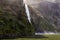 Landscape with a small waterfall and a mountain overgrown with greenery. Fiordland National Park. South Island, New Zealand