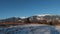 Landscape of snow covered agricultural field with some clumps of grass peeping out.