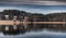 Landscape of a specular reflection in the lake, a dry grass, a cane and snags in the foreground, mountains and the