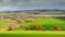 Landscape in spring. Dark rain clouds and green meadows. Village in sunlight