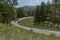 Landscape of springtime nature with mountain, green glade, coniferous forest and road