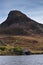 Landscape of steep hill peak with small boathouse on lake in for