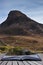 Landscape of steep hill peak with small boathouse on lake in for