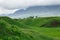 Landscape summer and spring. Bright green grass on the round hills. Clouds before the rain. Clouds in the sky. Tourism travel