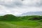 Landscape summer and spring. Bright green grass on the round hills. Clouds before the rain. Clouds in the sky. Tourism travel