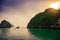 Landscape during sunrise with karst stone rocks and a fishing boat sailing out into the ocean