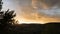 Landscape of a sunset with backlit trees that are trimmed over a beautiful cloudy sky