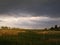 Landscape thunderclouds over the field and trees in a summer day in the village