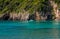 Landscape with turquoise calm sea water, mountain caves and touristic boat