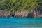 Landscape with turquoise calm sea water, mountain caves and touristic boat