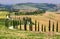 Landscape in Tuscany with road, castle and cypress trees, Italy.