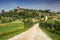 Landscape in Tuscany with road, castle and cypress trees, Italy.