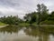 Landscape with Ukrina river and green riparian zone and underwater weed, natural ecosystem during cloudy summer day