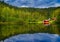 Landscape with vibrant colour in sky, green forest and calm tranquil reflections in water, beauty in nature.