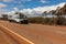 Landscape view of 4WD and modern caravan on an outback highway in Australia under a blue cloudy sky