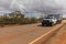 Landscape view of 4WD and modern caravan on an outback highway in Australia under a blue cloudy sky