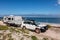 Landscape view of 4WD and modern caravan parked adjacent to a sparkling sunny beach