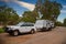 Landscape view of a 4WD and modern caravan parked next to green trees beside a highway