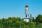 Landscape view of beautiful belfry on the riverside between lush greens