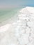 Landscape view on Dead Sea salt crystals formations, clear cyan green water at Ein Bokek beach, Israel