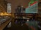 Landscape view of elevated `el` train crosses a still Chicago River with Christmas/holiday lights