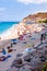 Landscape view on famous Rotonda Beach full of resting sunbathing and swimming people. Popular sea promenade in Tropea city in