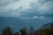 Landscape view of green hills covered with forest under floating clouds during late evening time