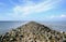 Landscape view of Kejawanan Beach Pantai seashore with rocks pathway, blue clear sky, sea water, Cirebon, West Java, Indonesia