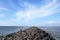 Landscape view of Kejawanan Beach Pantai seashore with rocks pathway, blue clear sky, sea water, Cirebon, West Java, Indonesia