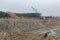 Landscape view of limestone quarry with large excavator machinery, high cliffs and canyons, and water