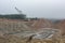 Landscape view of limestone quarry with large excavator machinery, high cliffs and canyons, and water