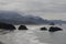 Landscape view of the rocks in the Canon Beach in Oregon with hills on a clouded day