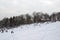 Landscape view of a snowy hill with families with children sledging and having fun in snow, Cmrok in Zagreb