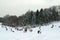 Landscape view of a snowy hill with families with children sledging and having fun in snow, Cmrok in Zagreb