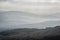 Landscape view from top of mountain on misty morning across countryside with fading layers