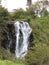 landscape with waterfall in mountainous area and temperate forest