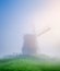 Landscape with windmill during fog. Holland. Dawn during a thick fog. Agricultural fields and pastures.