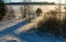 Landscape with winter road with orange rays of the setting sun.