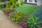 A landscaped small front yard with different plants and synthetic turf.