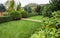 Landscaping of a garden with a bright green lawn, colorful shrubs, decorative evergreen plants and shaped boxwood Buxus