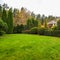 Landscaping of a garden with a green lawn, colorful decorative shrubs and shaped yew and boxwood, Buxus, in autumn.